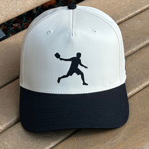 White and black baseball cap with a black silhouette of a player on a wooden surface